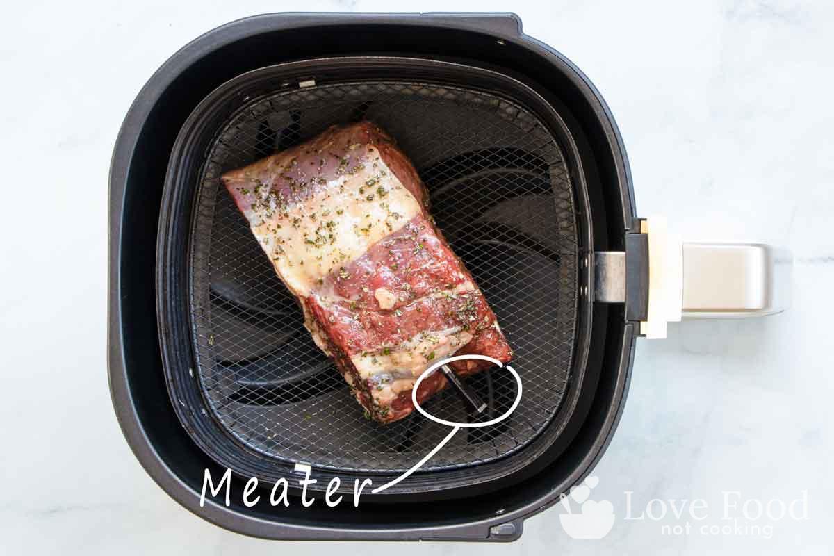 rib eye roast in air fryer basket with Meater meat thermometer.