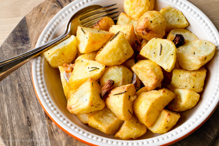 Air fryer roast potatoes in a white serving bowl.