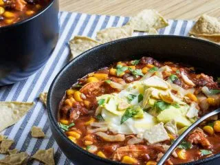 Slow cooker spicy chicken tortilla soup in a black bowl