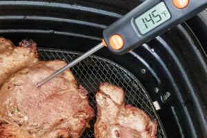 Instant read meat thermometer showing 145F in air fried lamb chops.