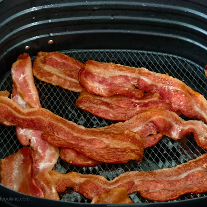 Crispy air fried bacon in the air fryer basket.