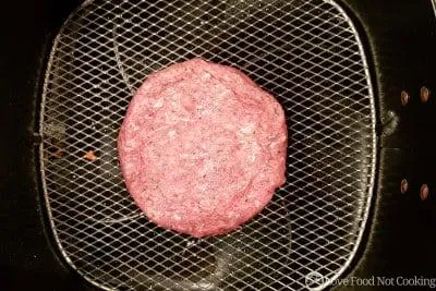 Hamburger in air fryer basket. 