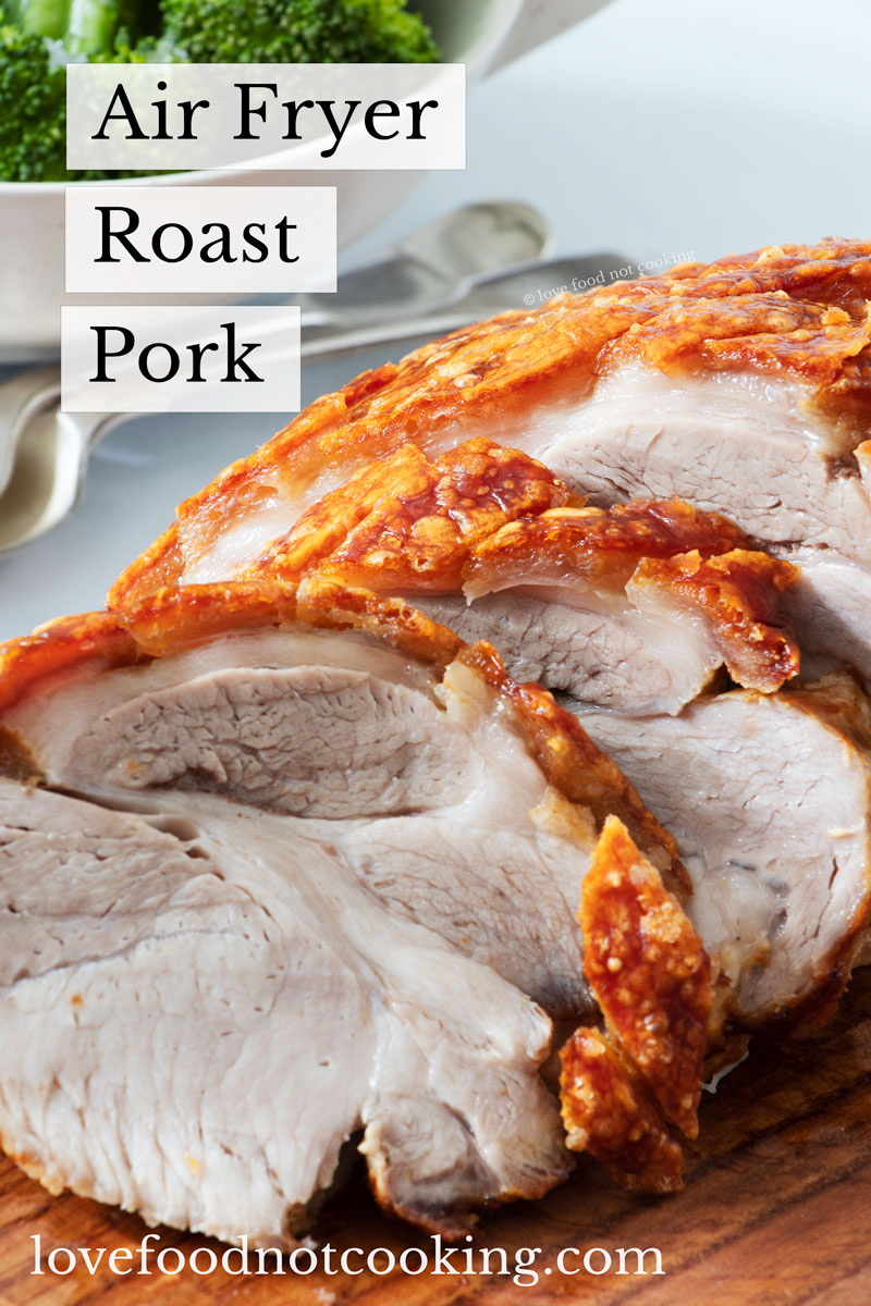 Air fried roast pork sliced on a wooden board with text overlay: air fryer roast pork. 