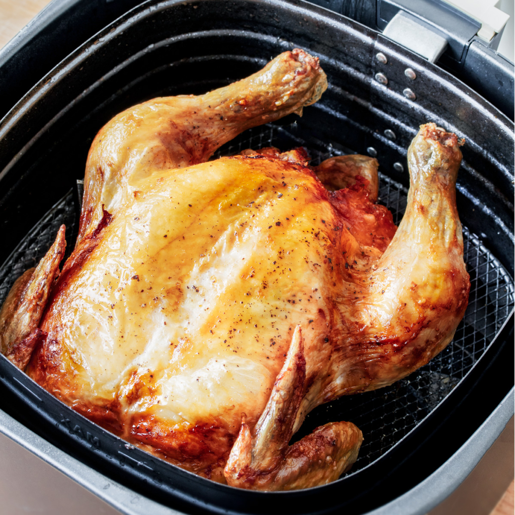 Roasted whole chicken in air fryer basket. 