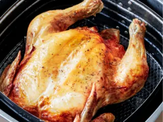 Roasted whole chicken in air fryer basket.