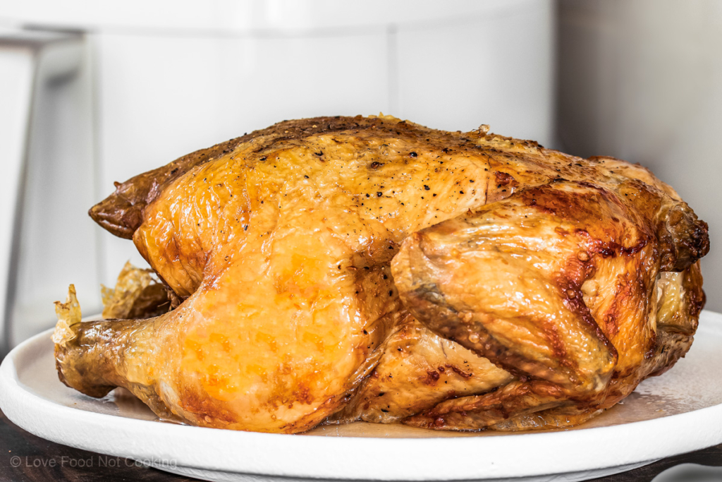 Air fryer whole roast chicken on a white plate.
