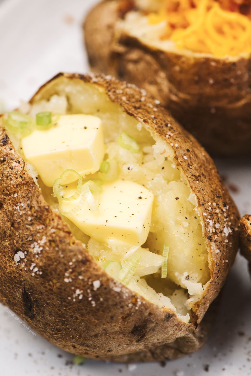 Air fryer baked potatoes with melted butter and cheese.