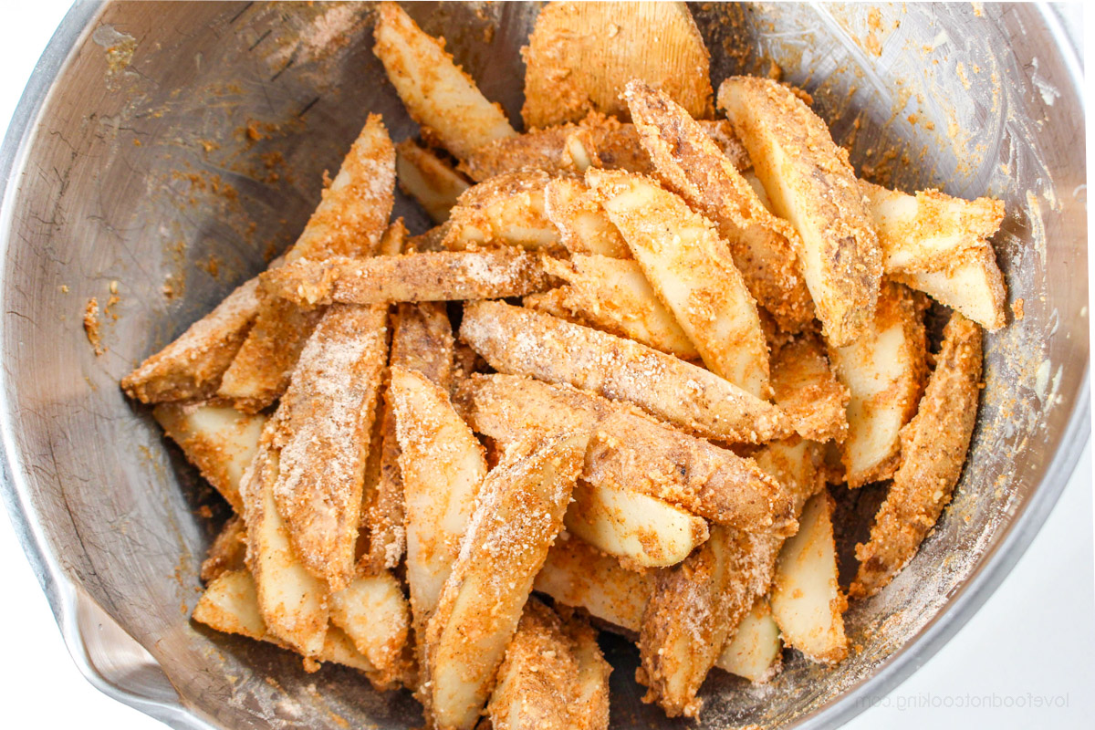 Uncooked coated wedges in a steel mixing bowl. 