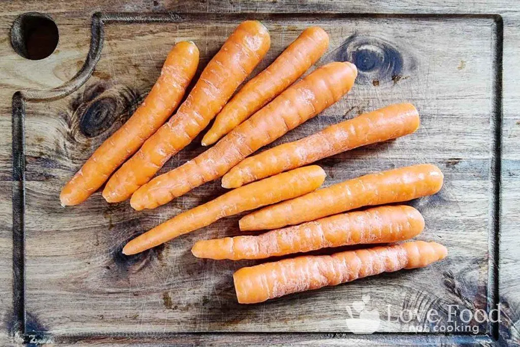 Baby carrots (scrubbed clean) on a wooden board. 