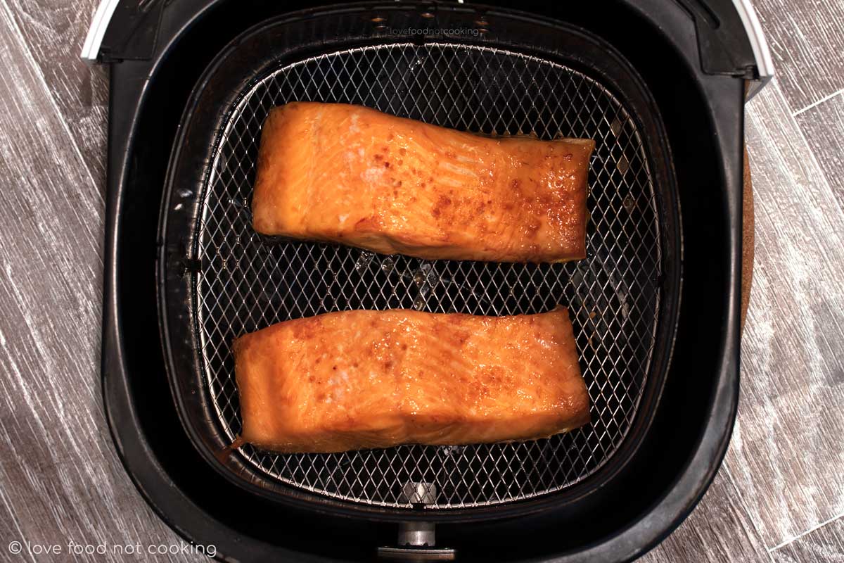 Cooked salmon in air fryer basket.
