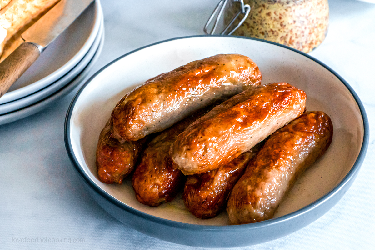 Air fryer sausages on a white plate.