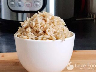 a white bowl of brown rice in front of an Instant Pot.