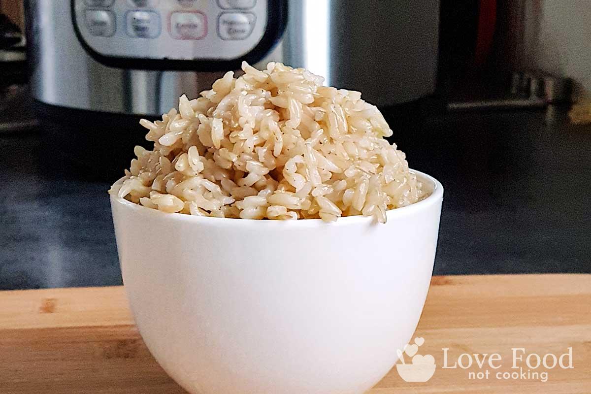 a white bowl of brown rice in front of an Instant Pot.