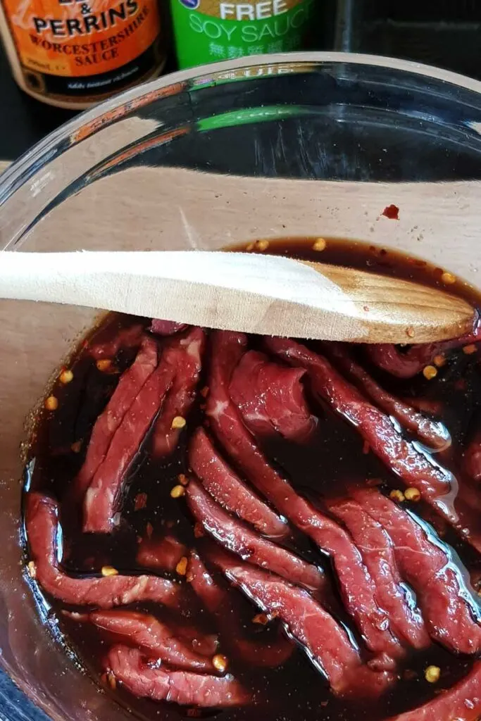Beef jerky marinating in a glass bowl. 