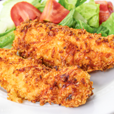 Air fryer chicken tenders on a white plate with salad.