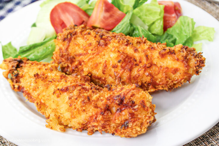 Air fryer chicken tenders on a white plate with salad.