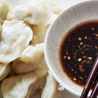 Steamed Dumplings om a plate with a bowl of dipping sauce