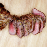 Sliced air fryer beef tenderloin on a wooden board.