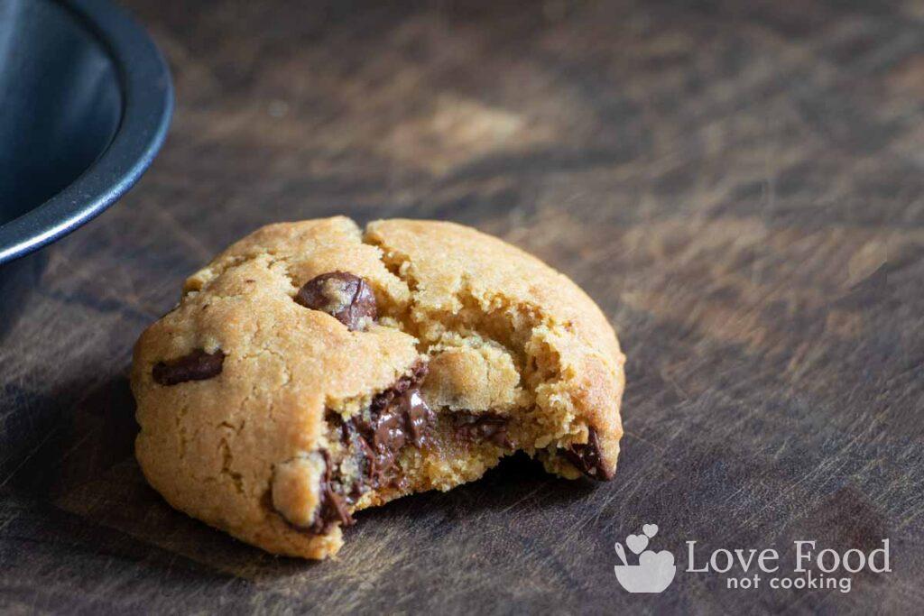 A cookie with a bite taken from it on a wooden board