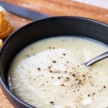 Instant Pot Potato and Leek Soup in a black bowl with crusty bread