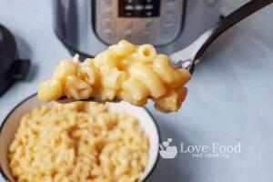 A forkful of mac and cheese in front of an Instant Pot