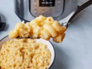 A forkful of mac and cheese in front of an Instant Pot