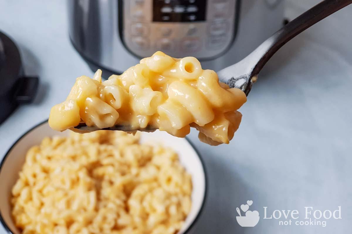 A forkful of mac and cheese in front of an Instant Pot