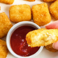 A hand holding a mac and cheese bite