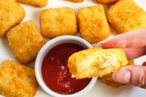 A hand holding a mac and cheese bite
