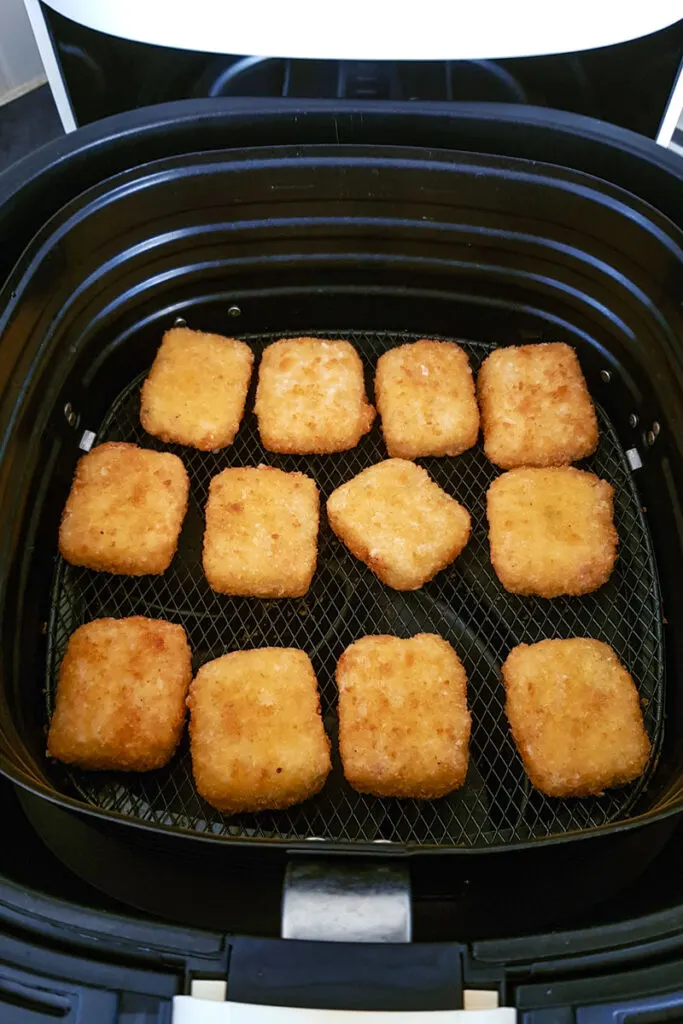 Air fried mac and cheese bites in air fryer basket. 