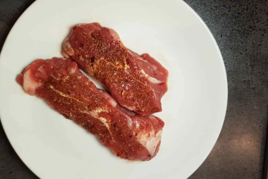 Seasoned lamb steaks on a white plate