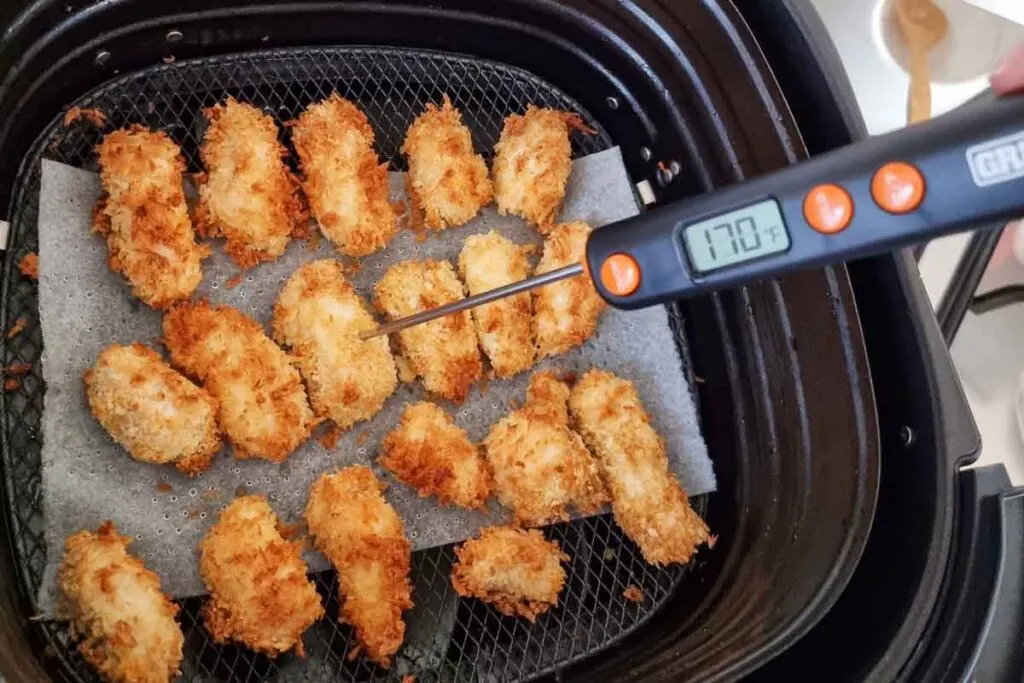 Air fried popcorn chicken being tested with a meat thermometer - temp shows 170F. 
