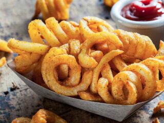 Curly fries in a white bowl.