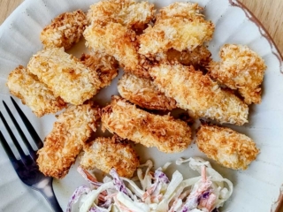 Crispy golden popcorn chicken on an plate with slaw.