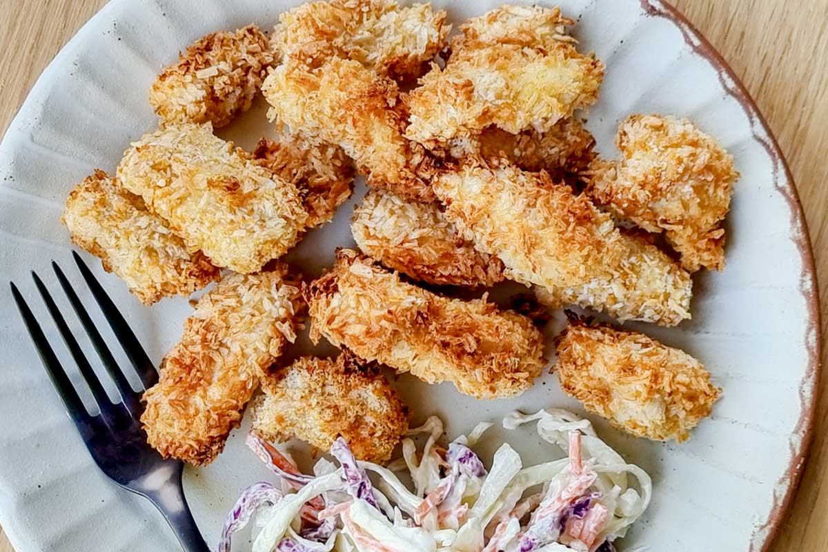 Crispy golden popcorn chicken on an plate with slaw. 