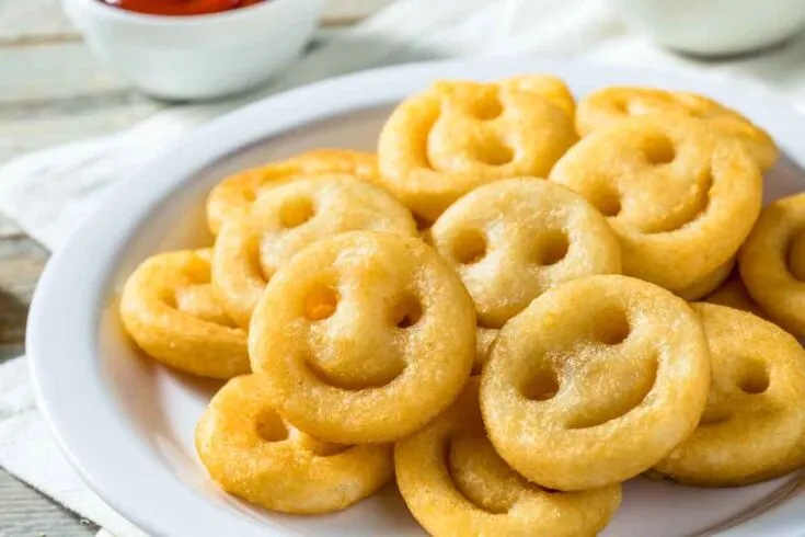 Golden brown smiley fries on a white plate.