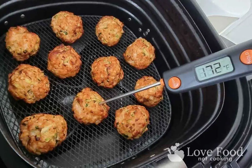 Cooked chicken meatballs in air fryer, instant-read thermometer reads 172F. 