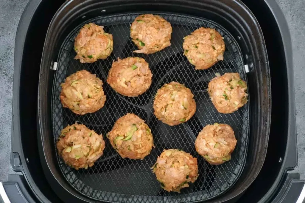 Chicken meatballs in air fryer basket. 