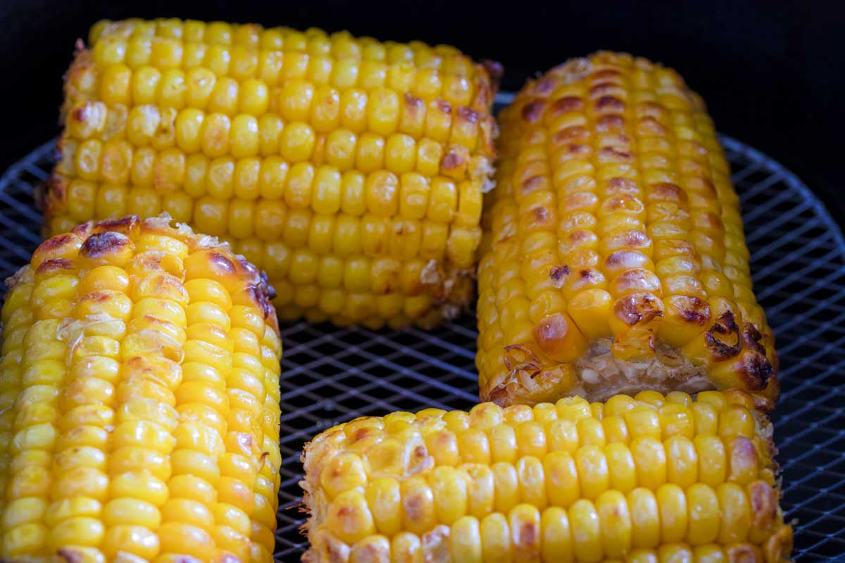 Air fried corn on the cob in air fryer basket.