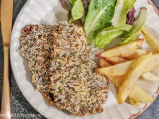 Air fryer beef schnitzel with fries and salad on a cream plate.