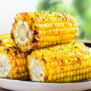 A stack of air fryer corn on the cob on a black plate.