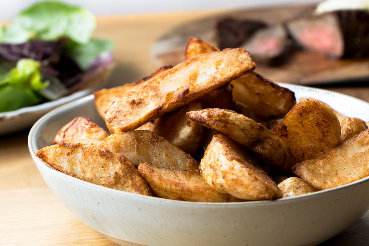 A grey bowl of air fried frozen potato wedges. 
