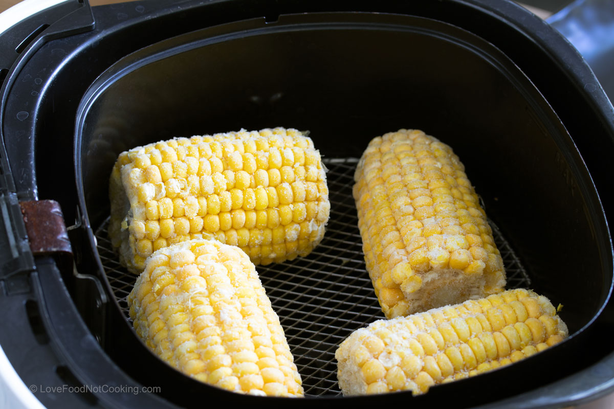 Frozen corn on the cob in air fryer basket. 