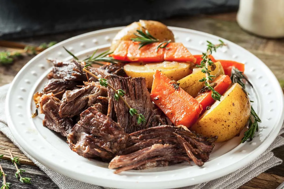 Slow cooked beef pot roast on a white plate.