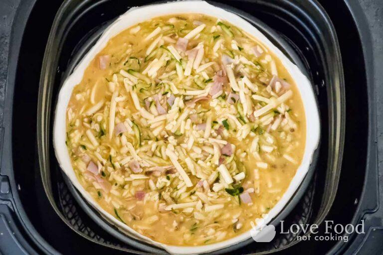 Uncooked quiche in air fryer basket.