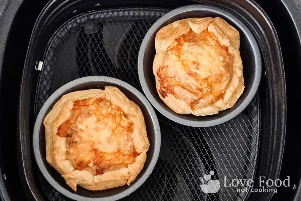 Cooked mini quiche in air fryer basket, golden brown and flakey. 