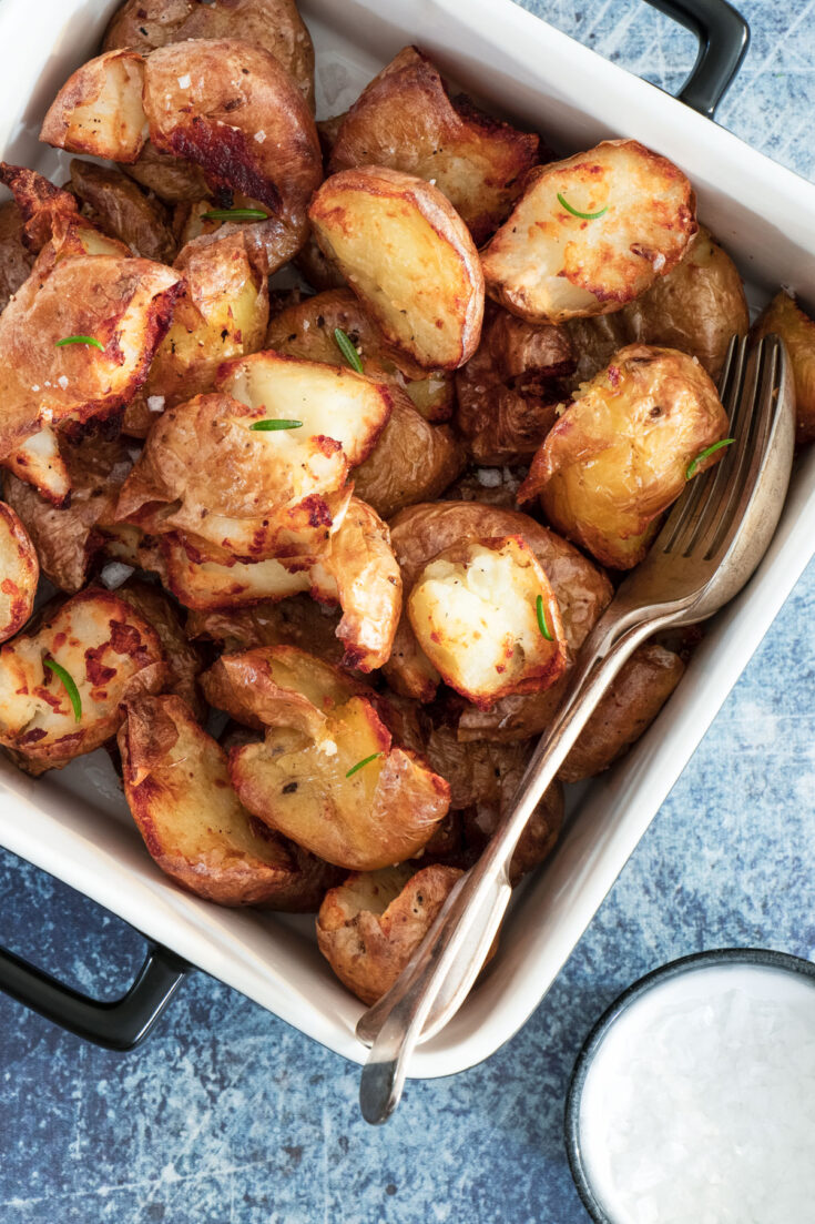 Air fried smashed potatoes in a white serving dish. 