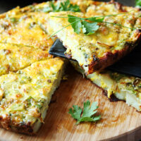 Air fryer frittata cut into slices on a wooden board.