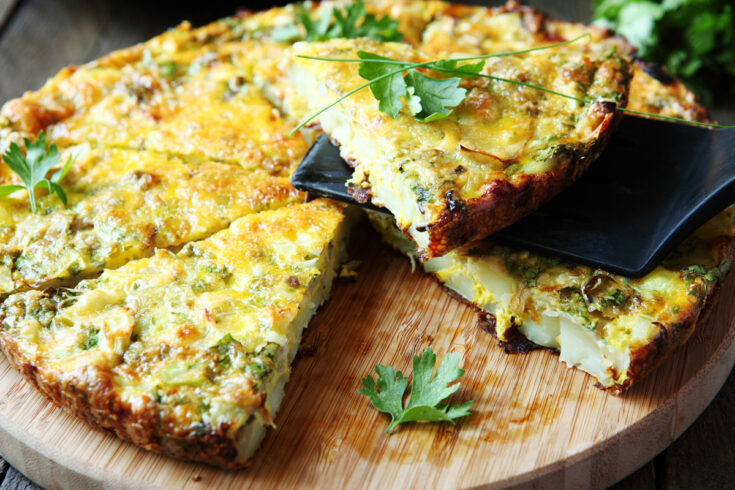 Air fryer frittata cut into slices on a wooden board.