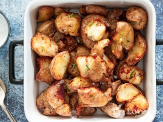 Air fryer smashed potatoes in a white serving dish.